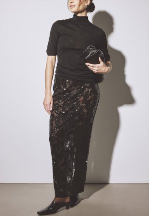 Čierny krátky rukáv s rolákom skombinovaný s čiernou sukňou so flitrami, ktorá má štruktúrovaný vzor, doplnený čiernym psaníčkom a topánkami s špicatou špičkou.