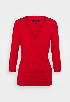 Haut féminin rouge à manches longues, ajusté, avec un profond décolleté en V et un design noué froncé à l'avant.