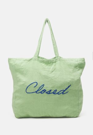 Grön linnehandväska med broderad blå text "Closed", utrustad med två handtag och en rymlig, mjuk textur.