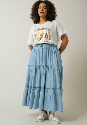 Jupe maxi bleu clair à volants avec taille élastique et cordon de serrage. Associée à un t-shirt blanc avec un graphique floral doré. Baskets blanches.