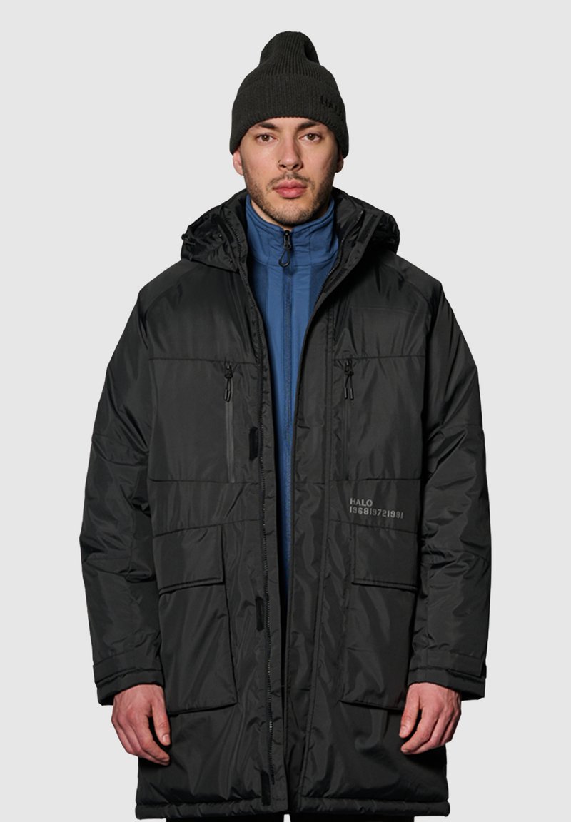 Czarna kurtka puchowa z kapturem, z niebieską wewnętrzną warstwą, wieloma przednimi kieszeniami i zapięciami na zamek. Obecne mankiety ściągane i szczegóły z logo.