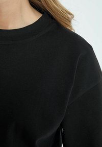 Zwarte katoen sweatshirt met een ronde halslijn en lange mouwen, met een gladde textuur en een minimalistisch ontwerp.