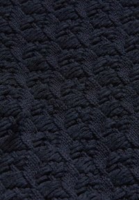 Tessuto knit blu navy con un motivo testurizzato caratterizzato da filamenti intrecciati in rilievo, creando un aspetto vissuto e tessuto.