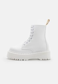 Botas de combate blancas con cordones, suela de plataforma gruesa y dentada, y una tira de tela marrón en la parte trasera, mostradas de perfil sobre un fondo blanco.