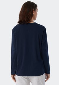Marinblus med lång ärm i mjukt tyg med en avslappnad passform, med rund halsringning och sömdetalj på baksidan, kombinerad med gråa sweatpants.