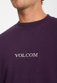 Sweatshirt violet en mélange de coton. Présente un col rond et une broderie blanche "VOLCOM" à l'avant. Tissu texturé.