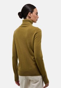 Pull col roulé vert olive à coupe ajustée, avec col et poignets côtelés. Texture douce, épaules sans coutures et ourlet droit.