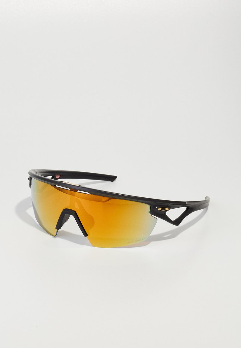 Sportsonnenbrille mit einem schlanken schwarzen Rahmen, großen orangefarbenen Verlaufslinsen und einem markanten, kantigen Design. Mit Ausschnitten in der Nähe der Schläfen.