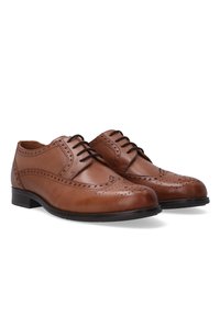Bruine leren schoenen met brogue-details, ronde neuzen en een lage zwarte rubberen zool. Beschikt over een vetersluiting en een gladde oppervlakte-textuur.