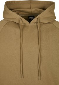 Felpa con cappuccio color sabbia realizzata in morbido misto cotone. Presenta un cordino, polsini a coste e maniche raglan senza cuciture. Finitura texturizzata.