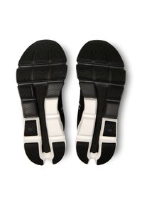 Black athletic shoe soles with textured rubber surfaces; features white sections and a segmented design for improved traction and flexibility.