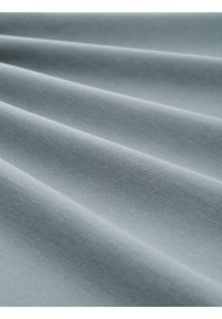 Tissu bleu clair avec une surface texturée, présentant des plis doux et une finition lisse. Le matériau semble durable et légèrement brillant.