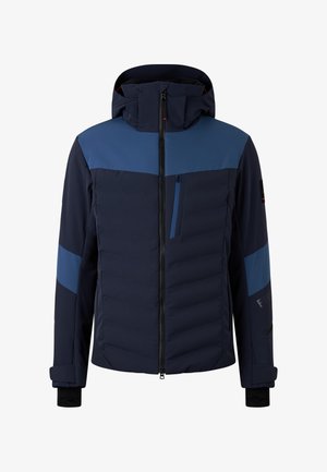 Marineblauwe jas met capuchon, voorzien van contrasterende blauwe panelen, een rits pocket op de borst, een gewatteerde textuur en elastische manchetten.