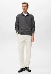 Dunkelgraues longsleeve Poloshirt, weißes Unterhemd, cremefarbene Hose und schwarze Schuhe. Einfaches Design mit klassischer Passform und minimalen Details.