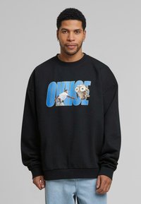 Hanorac oversized negru cu un design grafic care prezintă un bărbat și o bufniță, evidențiat de textul albastru "OHNSE". Material moale, croială relaxată.