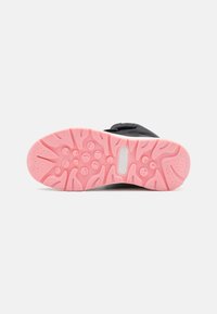 Botte noire avec une semelle en caoutchouc rose présentant des motifs de crans circulaires et ondulés, ainsi que le logo "KangaROOS" sur fond blanc.