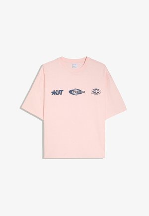 Világos rózsaszín rövid ujjú póló fekete grafikus szöveggel és szimbólumokkal: „*UT“, „FADED“ és „26“ a mellrészen.