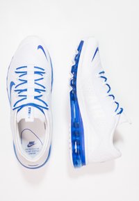 Vitaid sportskor i vitt med blå accenter, mesh-övre, synlig luftdämpning i hälen, snörningsdesign och strukturerad sula.