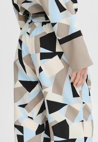 Conjunto de patrón geométrico multicolor que presenta tonos de azul, beige y negro; tejido texturizado con cintura elástica y pierna ancha.