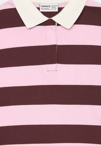 Randig polo i rosa och mörkbrun, med vit krage och mjukt bomullsmaterial. Kännetecknas av sina jämna horisontella ränder.