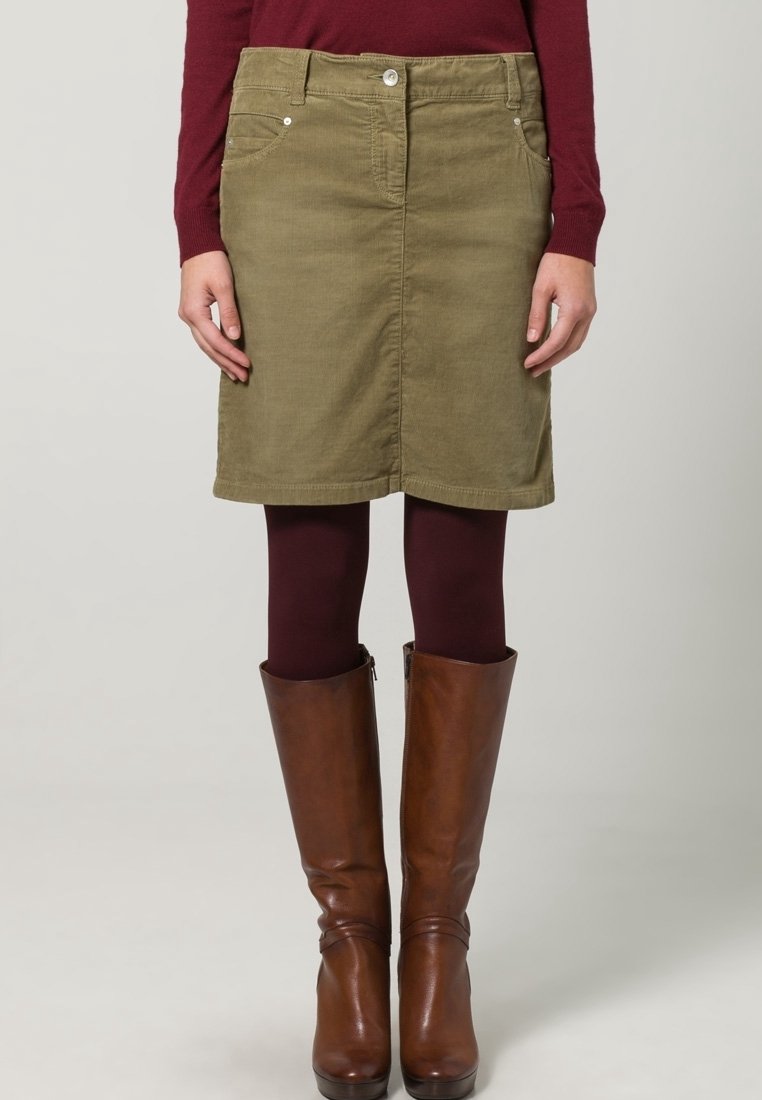Olijfgroene denim rok met een rechte snit, voorzien van voorkruisen en een knoopsluiting. Gepaard met bruine leren kniehoge laarzen.