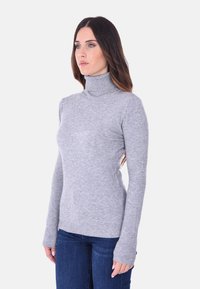Maglione grigio a collo alto realizzato in morbido tessuto a maglia, design aderente, maniche lunghe con polsini a coste, indossato con jeans blu.