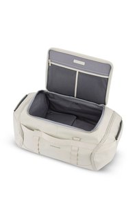 Sac de sport en matériau synthétique beige clair, avec un intérieur gris, fermeture éclair en haut, poche extérieure et anses doubles pour un transport facile.