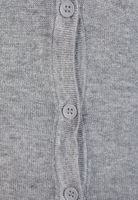 Grau gestrickte Strickjacke mit sechs abgerundeten grauen Knöpfen an der Vorderseite, die eine glatte Textur und gerippte Kanten zeigt.
