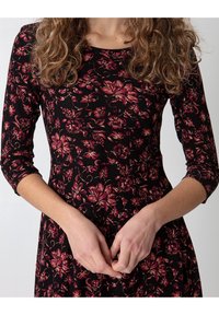 Black floral dress made of soft fabric, featuring a floral pattern in shades of pink and burgundy, with three-quarter sleeves and a round neckline.