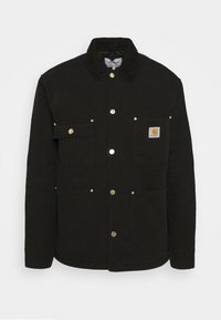 Sorte denimjakke med trykknaplukning, to frontlommer og et mærke med logo på brystet. Struktureret stof med krave.