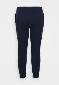 Námořnické modré tepláky vyrobené z měkké bavlněné směsi, s těsněním nohou, elastickým páskem a bočními kapsami. Hladká textura.