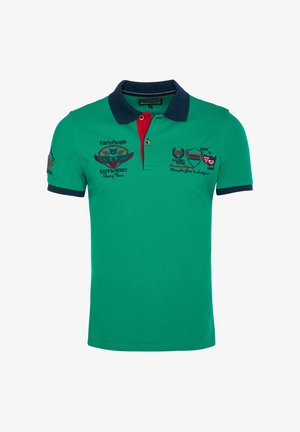 Grøn kortærmet poloshirt med navy krave og ærmekanter, rød placket-detalje og broderede racing-tema logoer på bryst og ærme.