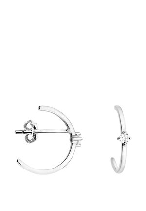 Silberne Creolen mit einer glatten, glänzenden Oberfläche; eine davon hat einen kleinen, diamantartigen Akzent. Das Design ist minimalistisch und modern.