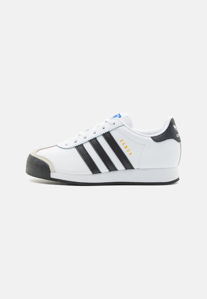 White sneakers with black stripes, textured leather upper, rubber toe cap, and suede accents. Features a blue label and gold "SAMOA" text.