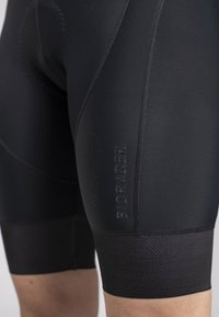 Black cycling shorts made of stretchy fabric, featuring flatlock seams, Bioracer logo, and textured leg bands for added grip.