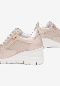 Baskets compensées en beige clair, avec un dessus en cuir brillant, des panneaux en mesh, des détails en zip doré et une semelle en caoutchouc blanc avec des motifs texturés.