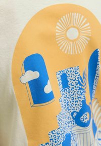 Camiseta de algodón de manga corta en color crema con un estampado gráfico en azul y amarillo que presenta formas abstractas, nubes y un patrón de sol.