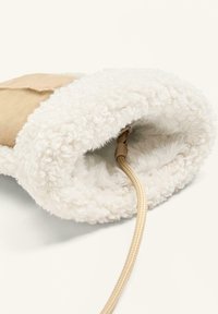 Világosbarna velúr külső réteg fehér bolyhos béléssel. Kerek formájú, bézs zsinórral és zsinórral belül. Puha textura az egész felületen.