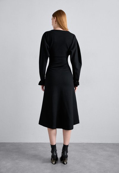 Black dress with a fitted bodice and flowing skirt. Features long sleeves with gathered accents at cuffs. Smooth fabric texture.