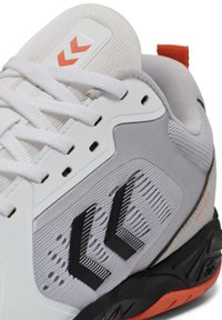 Witte en grijze sportschoen met een gestructureerde bovenkant, zwarte accenten en oranje details. Inclusief platte veters en een versterkte zool.