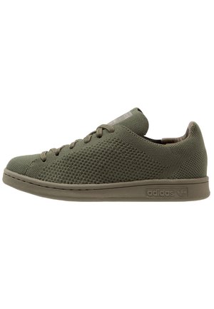 Low-top olivengrøn Adidas sneaker med strikket tekstur, snørebånd og gummisål, vist fra siden på en hvid baggrund.