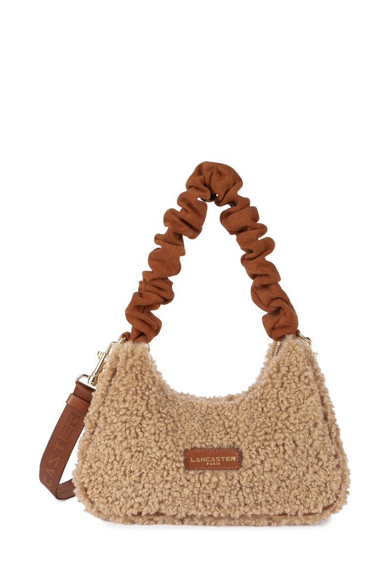 Sac à main en fausse fourrure beige avec une forme arrondie, une anse en style chouchou marron, et un accent en cuir avec un logo.