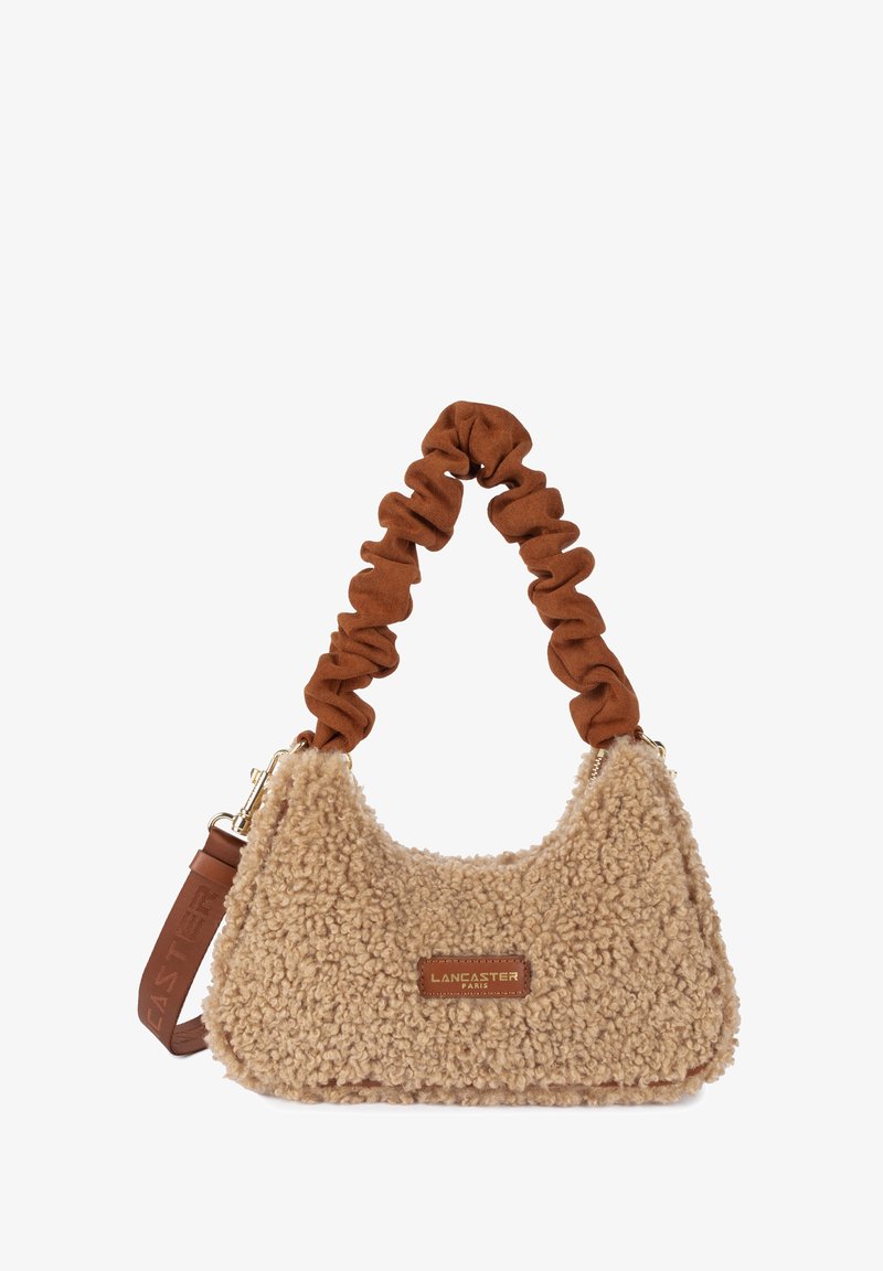 Sac à main en fausse fourrure beige avec une forme arrondie, une anse en style chouchou marron, et un accent en cuir avec un logo.