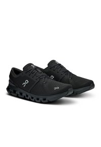 Baskets de sport noires avec une tige texturée, semelle extérieure en caoutchouc et semelle rembourrée. Comprend des lacets et des accents de logo sur les côtés.