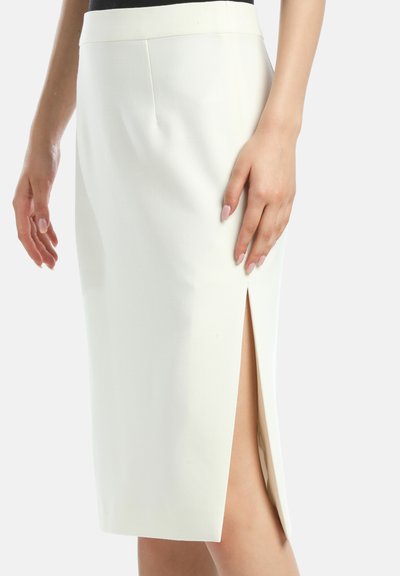 Valkoinen kynähame, jossa on korkea halkio, teksturoitu kangas, istuva leikkaus ja puhtaat linjat. Vyötärö on sileä, mikä lisää tyylikkään muotoilun ilmettä.