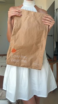 Brun papirhandlepose med rynket tekstur, som viser teksten "Elsk meg. Bruk meg." og en oransje form, merket "zalando".