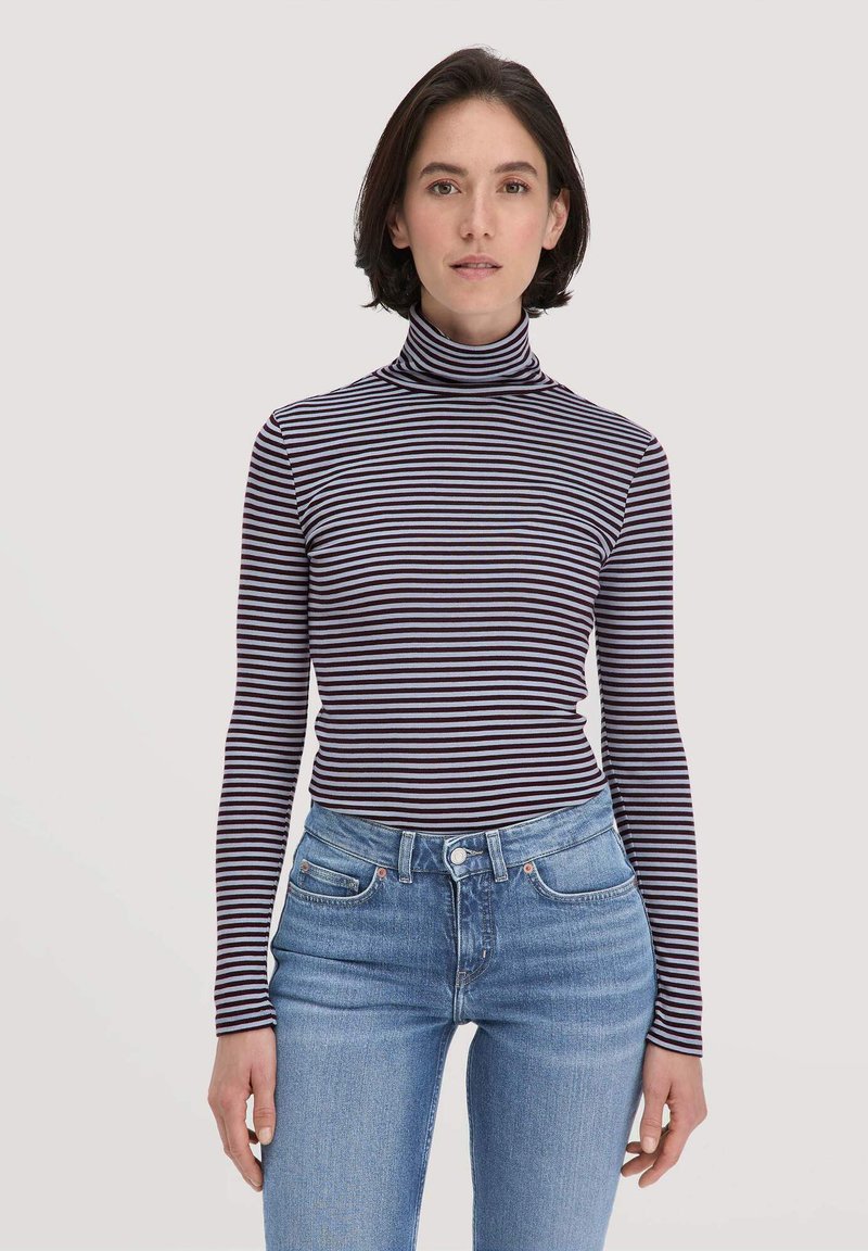 Langarm-Turtleneck mit dunkelblauen und helllila Streifen, aus weichem Stoff. Kombiniert mit mittelblauen, engen Jeans.