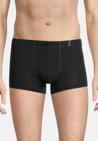 Black boxer briefs with green stitching, featuring a snug fit and a classic design. The waistband displays a small logo tag on one side.