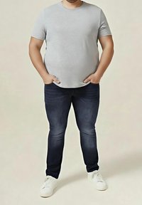 Camiseta gris de manga corta hecha de algodón, combinada con vaqueros de mezclilla azul oscuro y zapatillas blancas. Diseño simple con un ajuste clásico.