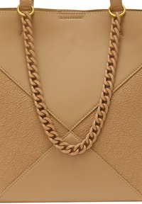 Läderhandväska i tan med texturerade paneler och släta detaljer, med ett kraftigt kedjehandtag och guldiga accenter.